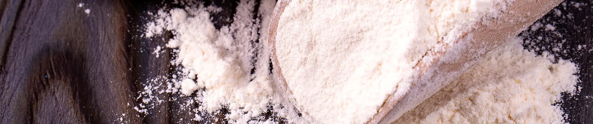 Scoop and pile of powdered stabilizers on wood — representing FDA-approved food stabilizers used for texture, consistency, and shelf life.