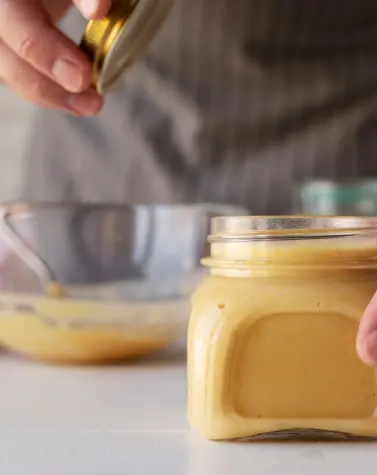 Jar of homemade food emulsifier with person sealing it in the background