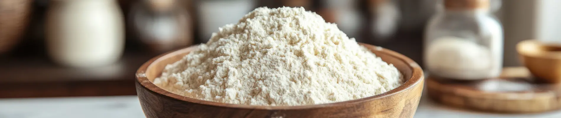 Wooden bowl with powdered food thickener, placed on a kitchen counter with jars in the background.