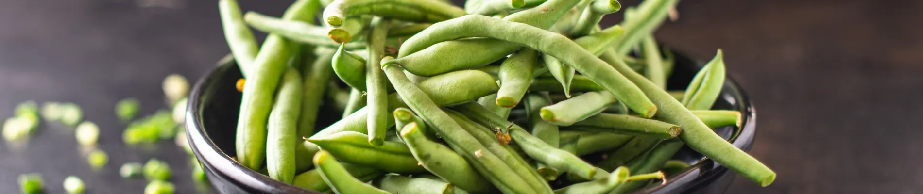 Black bowl filled with fresh green guar beans, representing the source of halal-certified guar gum.