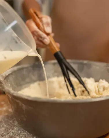 Close-up of hands mixing food ingredients in a bowl, representing the use of thickening and gelling agents in culinary processes.