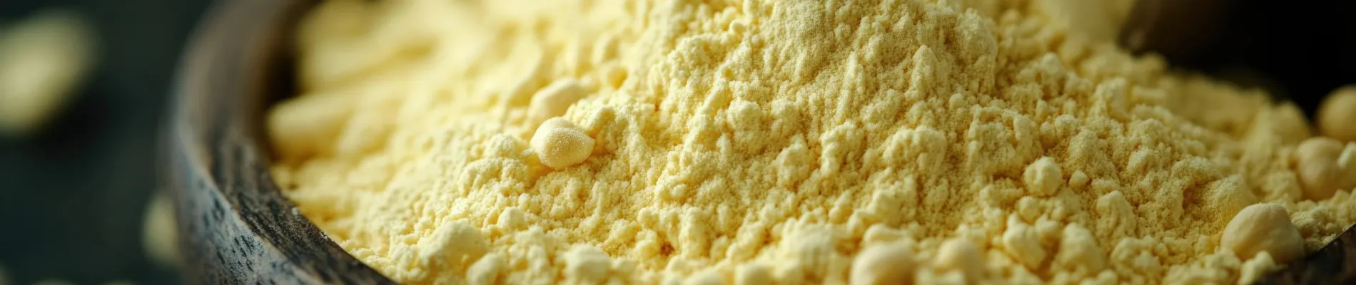 Close-up of Guar Hydroxypropyltrimonium Chloride powder in a wooden bowl with a wooden scoop in the background, showcasing its natural appearance.