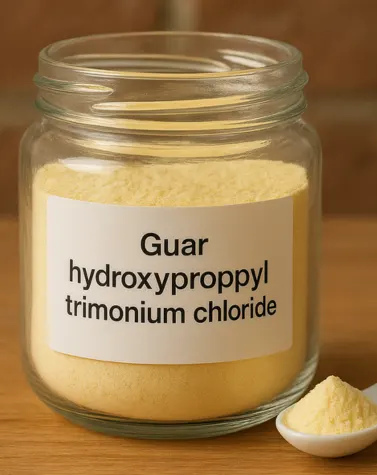 Glass jar of Guar Hydroxypropyltrimonium Chloride powder with a labeled container and a white spoon holding the yellowish cosmetic ingredient.